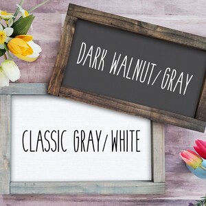 Op de afbeelding: Twee houten ingelijste borden met verschillende kleurcombinaties. Het bovenste bord is donkerwalnoot met grijze tekst die "DARK WALNUT/GRAY" luidt. Het onderste bord is klassiek grijs met witte tekst die "CLASSIC GRAY/WHITE" luidt.