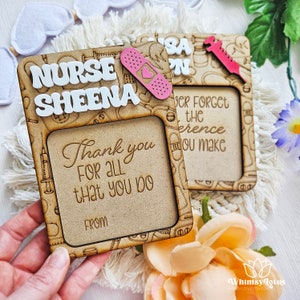 May include: A wooden frame with a cutout design of medical symbols and the words "NURSE SHEENA" and "Thank you for all that you do" with a space for a photo. The frame is decorated with a pink bandage with a heart.