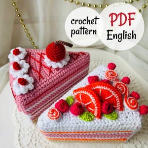 May include: Two triangular crochet cake slices. One is pink with white flowers and a red cherry on top. The other is white with orange slices, red berries, and green leaves. Text on the image reads: crochet pattern PDF English.