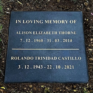 May include: A black granite headstone with gold lettering. The inscription reads "In loving memory of Alison Elizabeth Thorne 7.12.1960 - 31.03.2010" and "Rolando Trinidad Castillo 3.12.1943 - 22.10.2021".