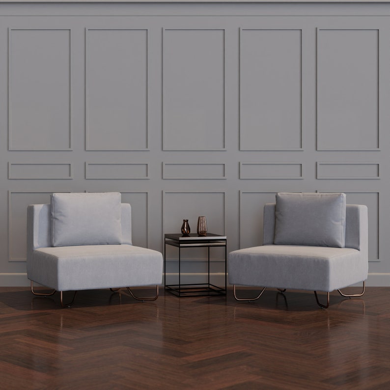 Puede incluir: Dos sillas blancas tapizadas con una mesa auxiliar de metal negro en una habitaci&oacute;n con paredes grises con paneles y suelo de madera oscura.