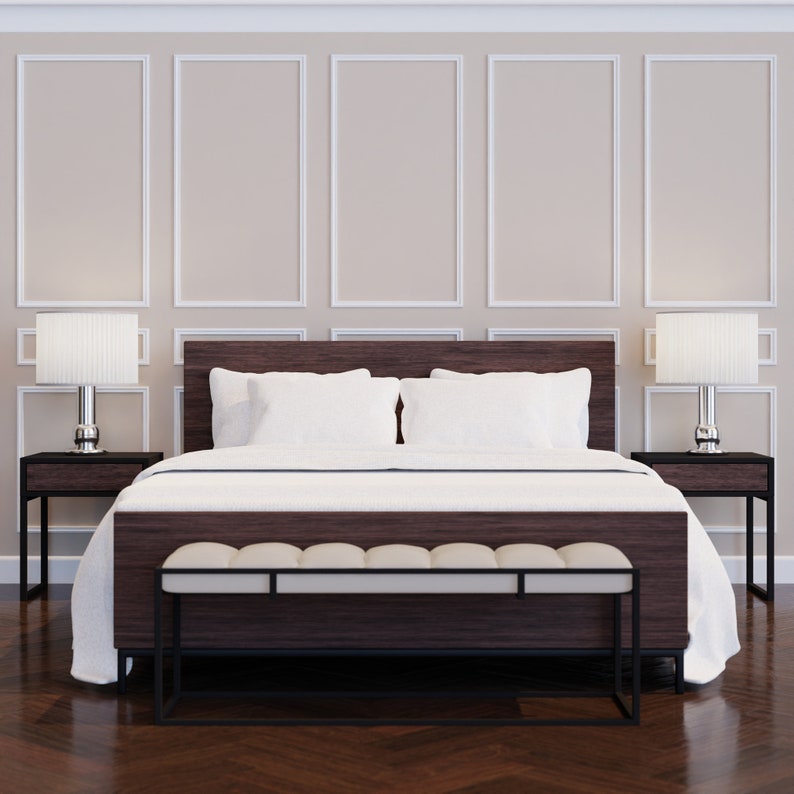 Puede incluir: Una cama con un cabecero blanco y ropa de cama blanca. La cama tiene un banco de madera oscura a juego al pie de la cama. Dos mesitas de noche con l&aacute;mparas est&aacute;n a cada lado de la cama. La habitaci&oacute;n tiene paredes blancas con molduras decorativas.
