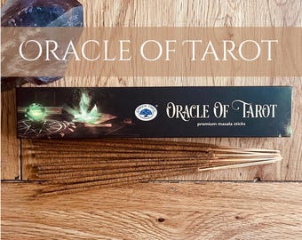 Puede incluir: Una superficie de madera muestra una caja de palitos de masala premium "Oracle of Tarot", con un cristal y el texto "Oracle of Tarot" en blanco. La caja es negra con un logotipo de árbol verde.