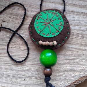 May include: A green and brown felt pendant necklace with a wooden bead accent. The pendant features a green circle with brown stitching and a brown circle with green stitching.
