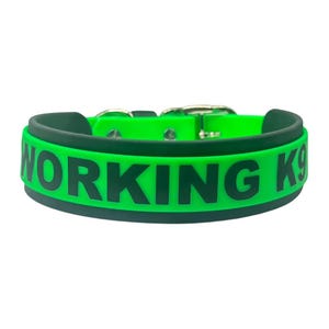 May include: A bright neon green dog collar featuring the bold black text WORKING K9 printed across the center. The collar is constructed from a smooth, flexible material and includes a silver-toned metal buckle and hardware for secure fastening.