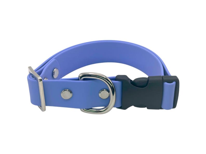 May include: A periwinkle blue dog collar with a black plastic buckle and a silver-colored metal D-ring and hardware. The collar is made of a flexible, waterproof material.