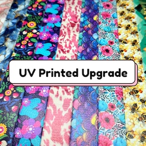 May include: A variety of colorful, patterned straps with the text "UV Printed Upgrade". The straps are made of a textured material and feature a variety of designs, including floral, geometric, and abstract patterns.