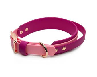 May include: A two-tone pet collar featuring a vibrant magenta inner strap and a soft light pink outer strap. The collar is equipped with rose gold-colored metal hardware, including a buckle, a D-ring for a leash, and two circular rivets.
