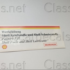 May include: A rectangular sticker with text in German and English. The sticker has a yellow, red, and white stripe at the top. The text includes "Shell Fuels and Shell Lubricants" and a product code.