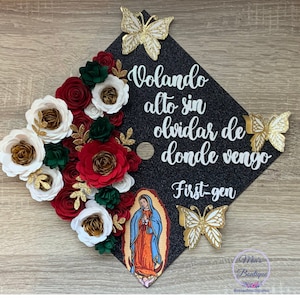 May include: Black graduation cap decorated with red, white and green paper flowers, gold butterflies, and a picture of the Virgin Mary. The cap also features the text "Volando alto sin olvidar de donde vengo" and "First-gen".