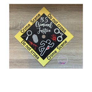 Op de afbeelding: Gele afstudeerhoed met zwart-witte misdaadscènetape en een zwart silhouet van een rennende persoon. De tekst op de tape luidt "Crime Scene Do Not Cross" en "B.S. Criminal Justice".