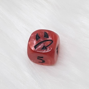 May include: Red dice with black markings. The dice has a five on one side and a devil symbol on another side.