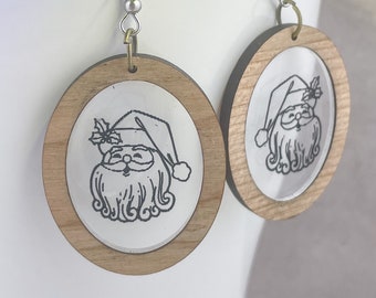 May include: A pair of wooden earrings with a clear resin insert featuring a black and white illustration of Santa Claus. The earrings have silver hooks.
