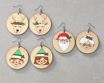 May include: Set of six wooden Christmas earrings featuring various holiday characters. The earrings are painted with red, green, white, and brown details. The characters include Santa Claus, a reindeer, an elf, and a snowman.