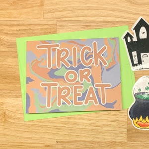 May include: A green card with a swirled orange, purple, and green background. The text "Trick or Treat" is written in a large, orange font.