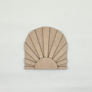 May include: A wooden sunburst wall decor with a light brown finish. The sunburst is made of multiple thin, vertical slats that radiate outwards from a central circle.