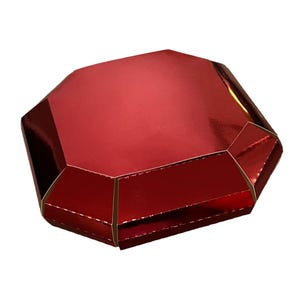 May include: A shiny, ruby-red gift box with a geometric, faceted design. The box has a metallic finish and a gold-colored trim. The shape resembles a large gemstone, perfect for jewelry or small gifts.