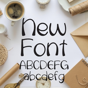 May include: A white surface with the words "New Font" in a bold, black, handwritten style. Below the text are the uppercase and lowercase alphabets. The image is surrounded by stationery items, including a cup of coffee, a clock, and scissors.