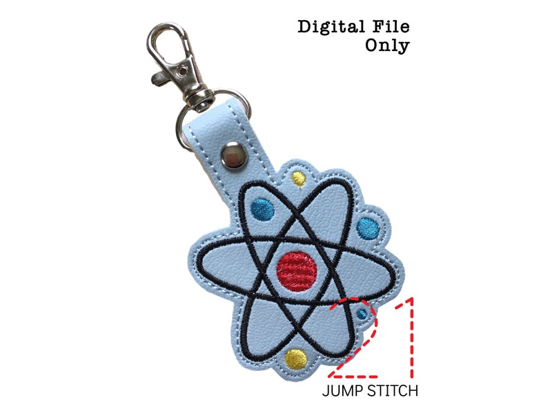 May include: A light blue leather keychain with an embroidered atom design. The atom is black with red, blue, and yellow accents. The keychain has a silver jump ring and a silver split ring.