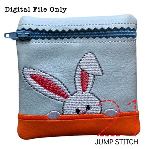 May include: A light blue zippered pouch with a white bunny embroidered on the front. The bunny has pink ears and is peeking out from behind a bright orange strip. The pouch has a jump stitch detail on the bottom.
