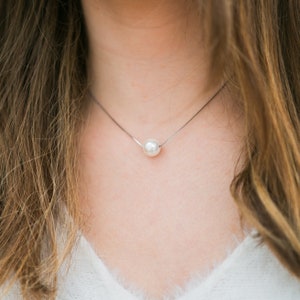 May include: A simple silver chain necklace with a single white pearl pendant.