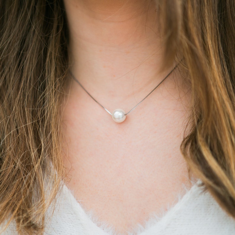 May include: A simple silver chain necklace with a single white pearl pendant.
