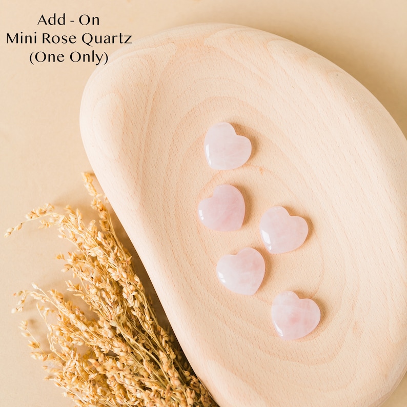 Op de afbeelding: Vijf roze kwarts hartvormige stenen op een houten oppervlak. Add-On Mini Rose Quartz (One Only)