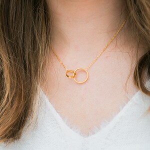 May include: A gold chain necklace with a pendant featuring two interlocking circles.