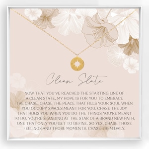 May include: A gold necklace with a compass pendant and a message card that reads "Clean Slate." The card has a floral design and the message encourages embracing a new beginning and chasing dreams.