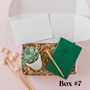 a box with a notepad, pen and succulents