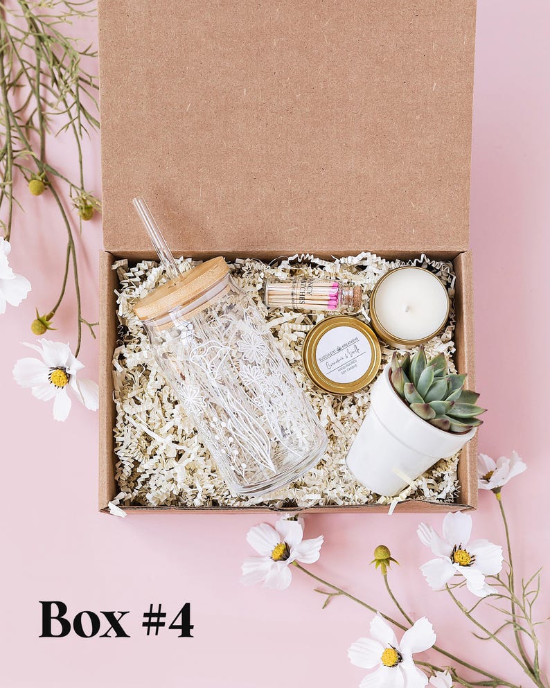 a box containing a candle, a glass jar, and a plant