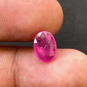 May include: A vibrant pink oval-shaped gemstone with a faceted cut.