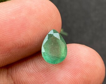 Puede incluir: Una piedra preciosa de esmeralda en forma de pera con un tono verde. La piedra preciosa está facetada y tiene un acabado liso y pulido.