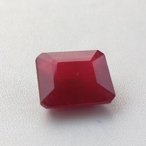 Könnte beinhalten: Ein tief roter Edelstein mit quadratischer Form und facettenreichem Schliff.