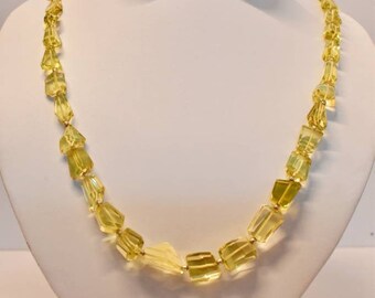 May include: A yellow citrine gemstone necklace with faceted beads. The necklace is displayed on a white mannequin bust.