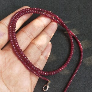 May include: A strand of deep red ruby beads with a silver clasp. The beads are faceted and have a polished finish.