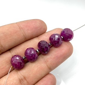 Puede incluir: Una hebra de seis cuentas de rubí facetadas, cada cuenta es de color rojo intenso y tiene una forma ligeramente redondeada.