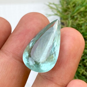 May include: A teardrop-shaped aquamarine gemstone with a light blue color and a faceted cut.