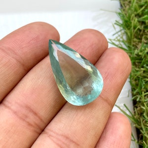 May include: A teardrop-shaped aquamarine gemstone with a light blue and green color.