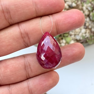 May include: A deep red faceted gemstone pendant in a teardrop shape.