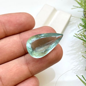 May include: A teardrop-shaped aquamarine gemstone with a light green hue.
