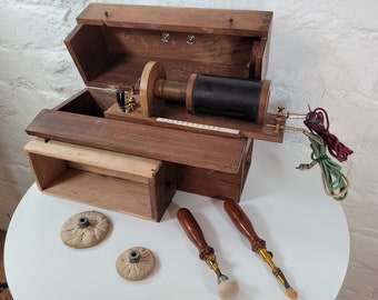 May include: Antique wooden box containing a vintage medical device with a coil, wires, and two probes. The box has a hinged lid and a small drawer. The device is used for medical treatments.