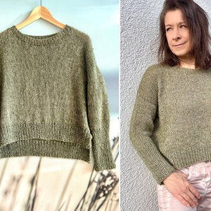 May include: A green knitted sweater with a round neckline and long sleeves. The sweater has a slightly cropped length and a textured knit.