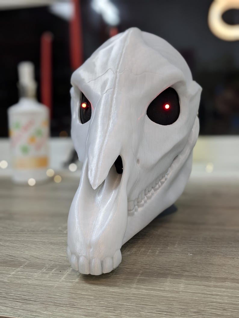May include: White 3D printed animal skull mask with red glowing eyes. The mask has a long snout and detailed teeth.