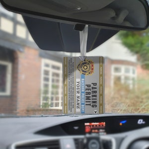 May include: A silver and blue parking permit for the Raccoon Police Department. The permit is valid from 1 November 1997 to 31 October 1998. The permit is hanging from a rearview mirror in a car.