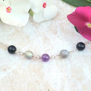 May include: A silver chain bracelet with black, grey, and purple gemstone beads.