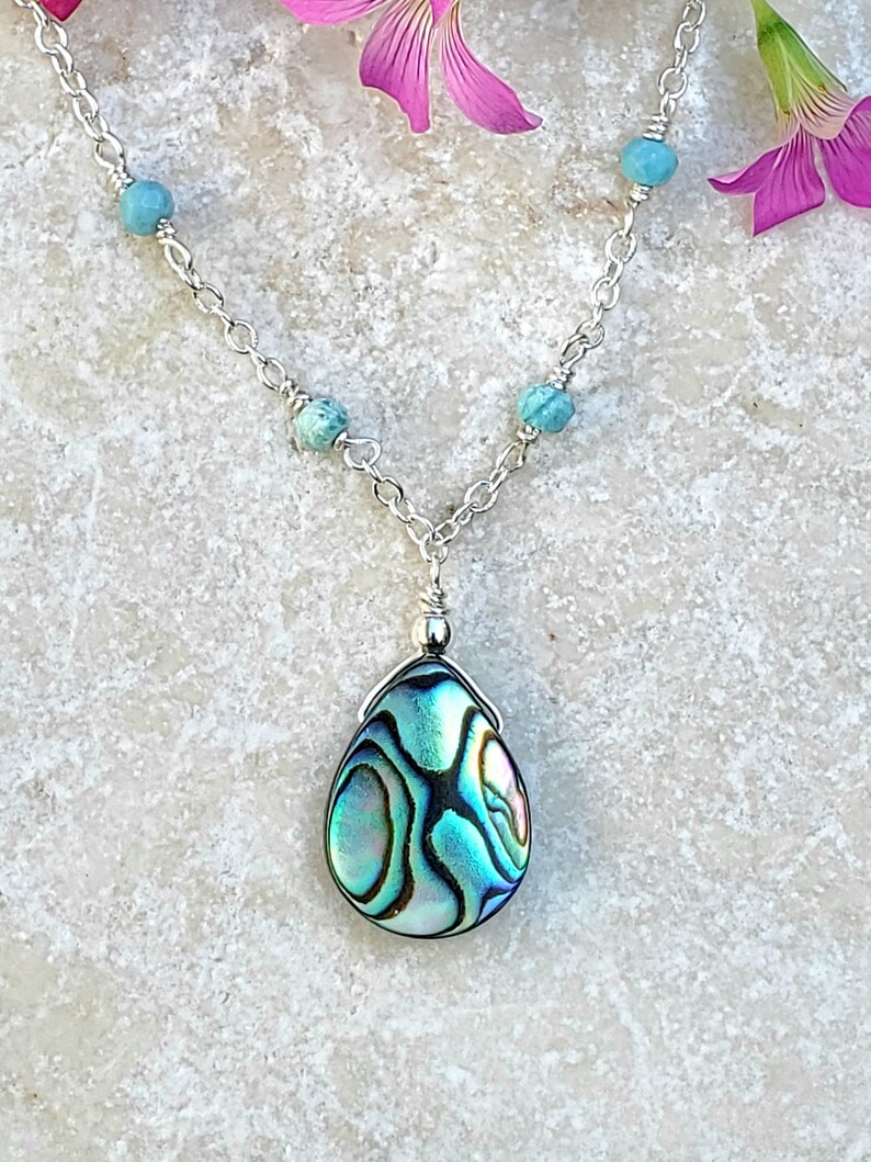 May include: A silver chain necklace with turquoise beads and a teardrop-shaped abalone shell pendant.