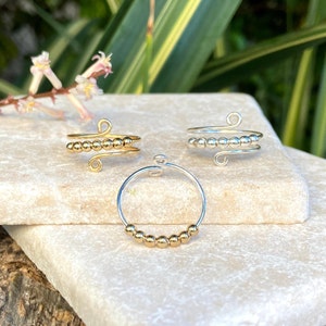 May include: Three gold and silver rings with small beads. The rings are made of wire and have a simple design.