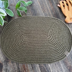 May include: A green oval crochet rug with a textured surface.