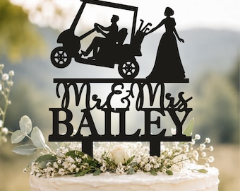 Op de afbeelding: Een zwarte taarttopper met een silhouet van een persoon in een golfkarretje en een persoon die ernaast staat. De tekst "Mr & Mrs" staat in cursief schrift boven de naam "BAILEY" in blokletters, met twee prikkers aan de onderzijde voor bevestiging.